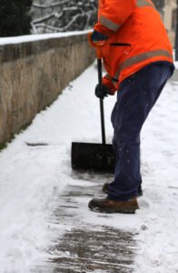 Worker shoveling snow from sidewalk, remove snow.